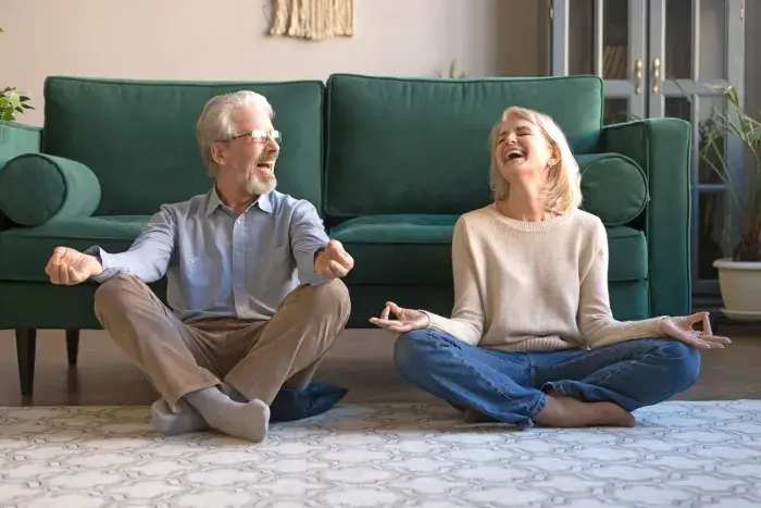 deux personnes séniors en position zen assis dans le salon 